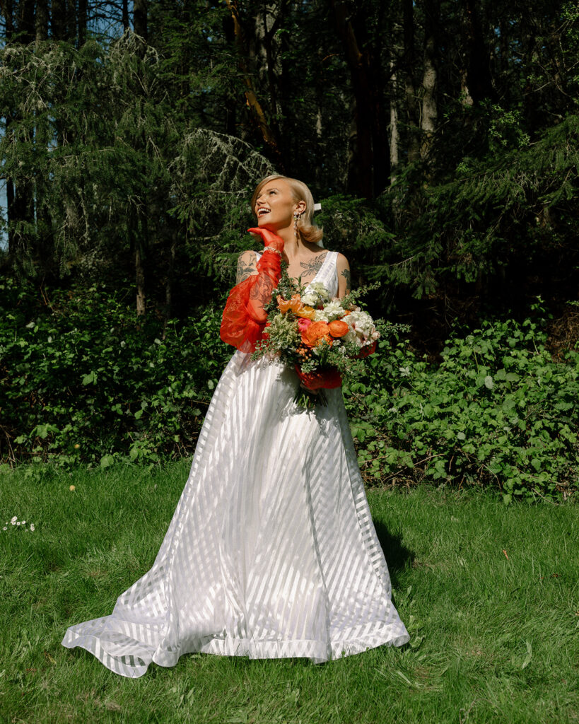 A Washington bride poses in her white gown and colorful orange accessories in a photo taken after her Vashon wedding.