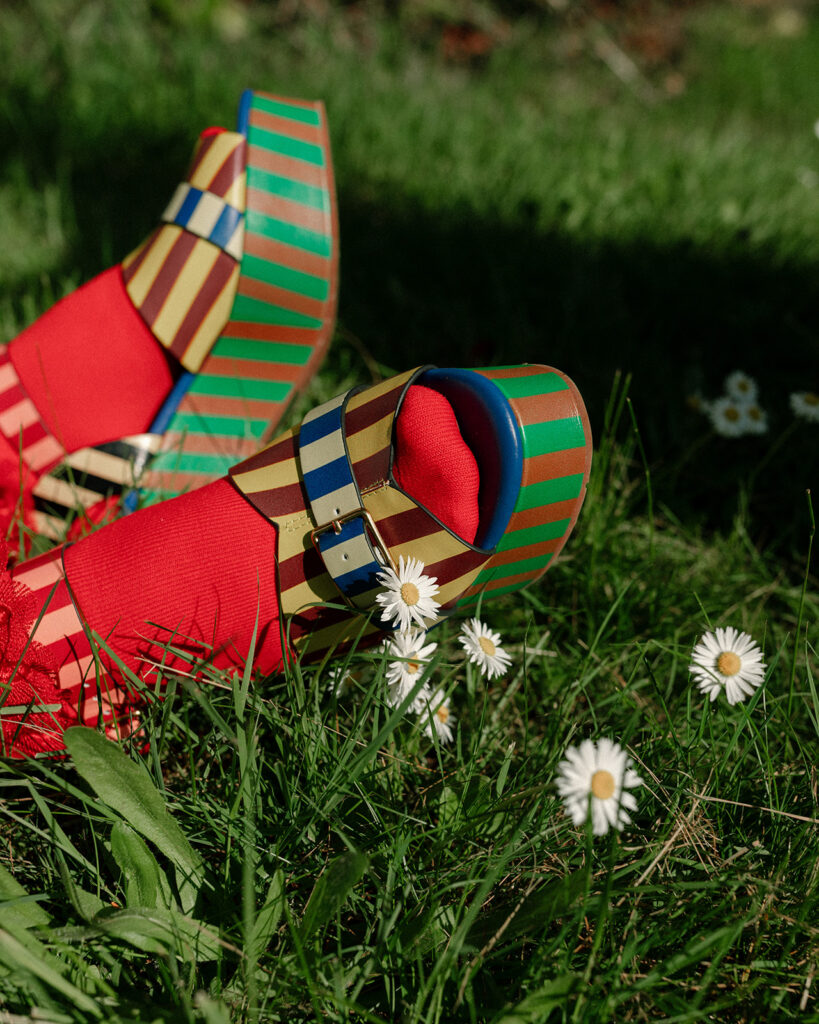A detail shot of a Washington bride's colorful platform shoes and orange socks next to wild daisies in the green grass of her Vashon Island wedding 