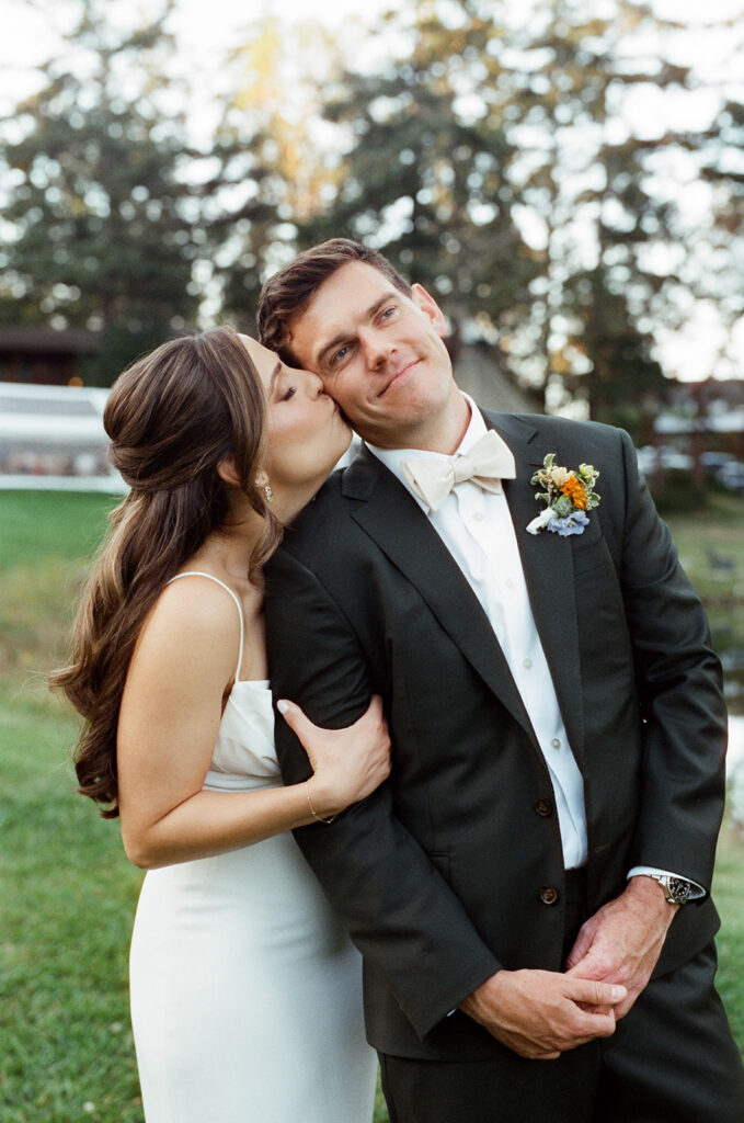 A bride kisses her groom on the cheek in their wedding attire at their Captain Whidbey Inn wedding 