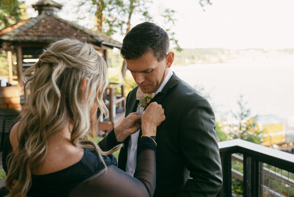A groom has his boutonniere pinned to his lapel before his Whidbey Island wedding 