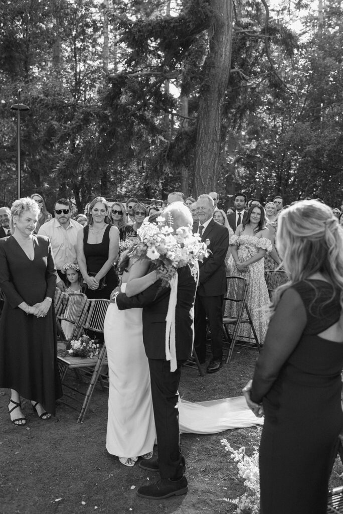 A bride and her father share a hug in a black and white image from her Whidbey Island wedding 