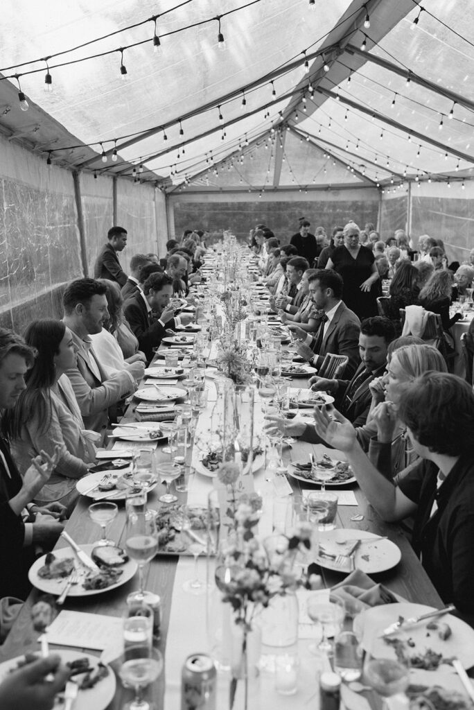 A black and white image of wedding guests enjoying dinner at a wedding reception held at the Captain Whidbey Inn in Coupeville WA
