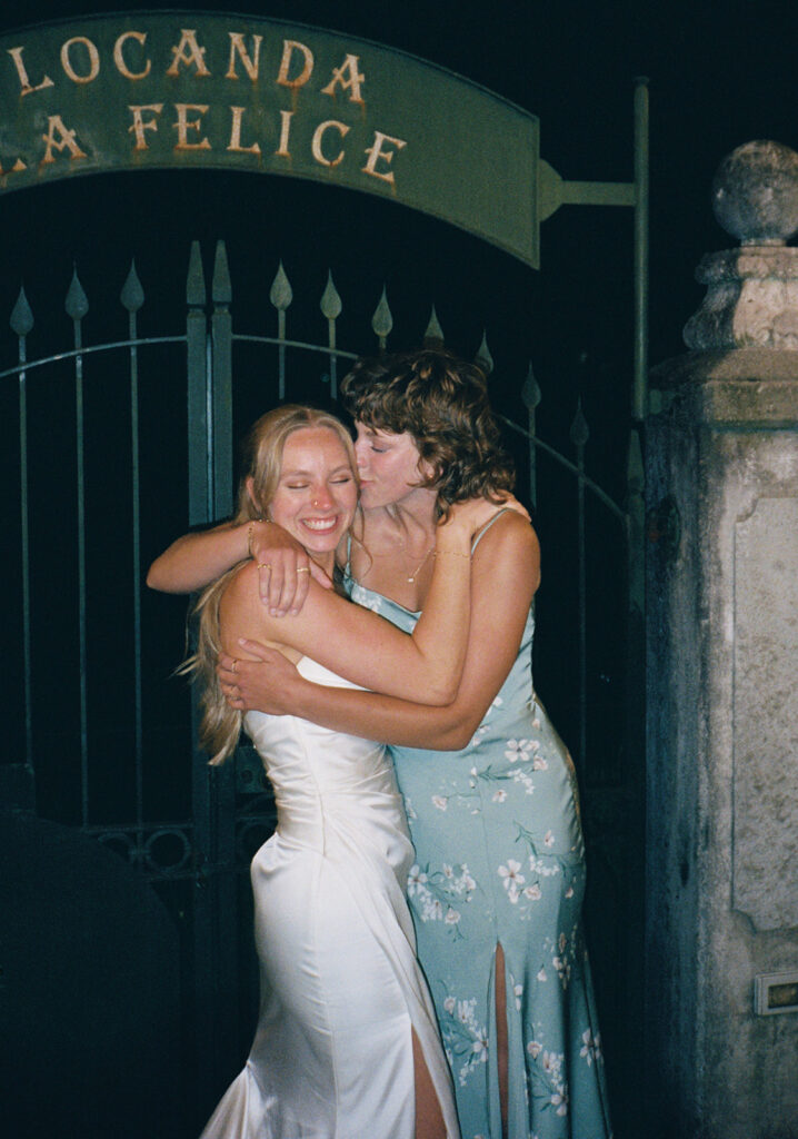 A bridesmaid and the bride share a hug following her destination wedding on lake como 