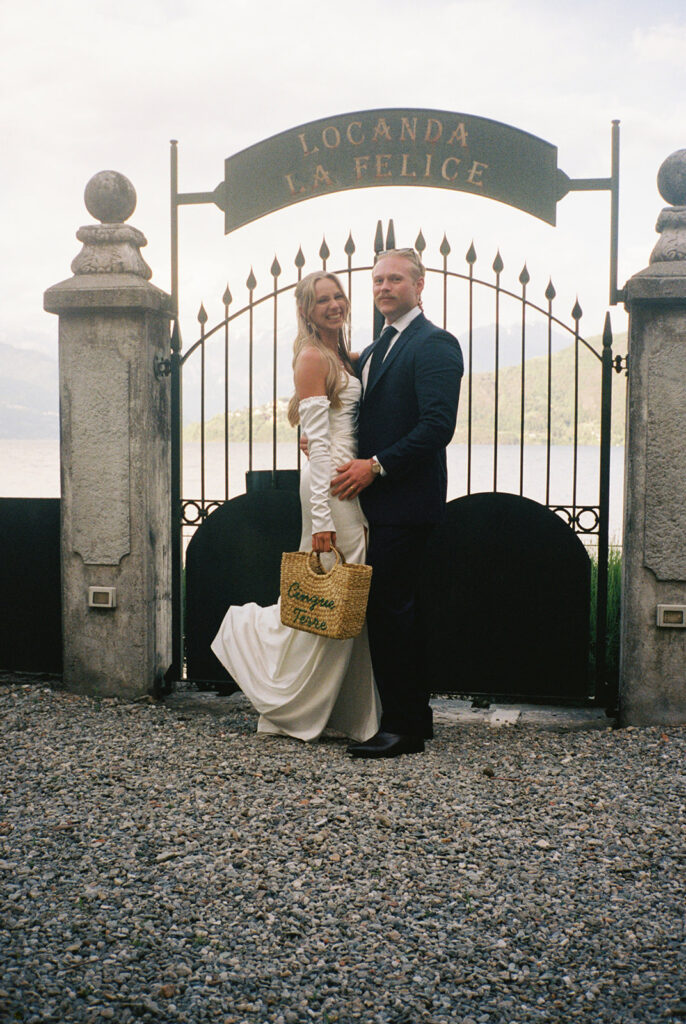 Newlyweds stand smiling before an iron gate at a destination wedding at Villa la Felice 