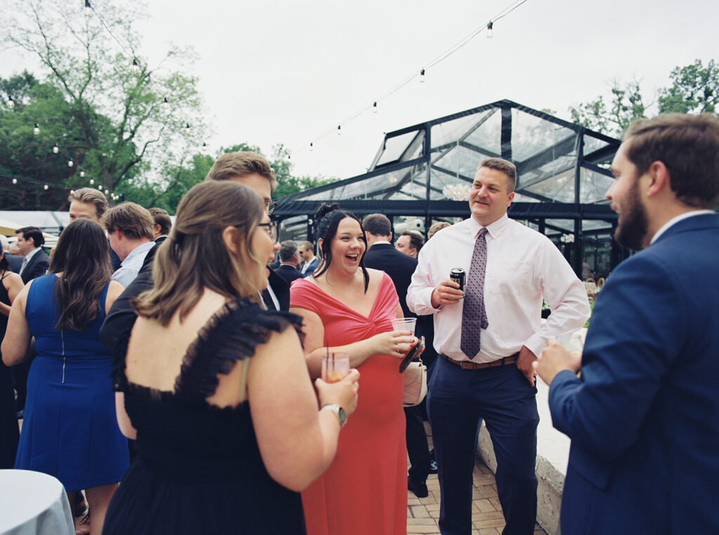 Guests at a bavaria downs wedding enjoy cocktail hour on the patio at Woodland Glasshaus in Chaska, MN