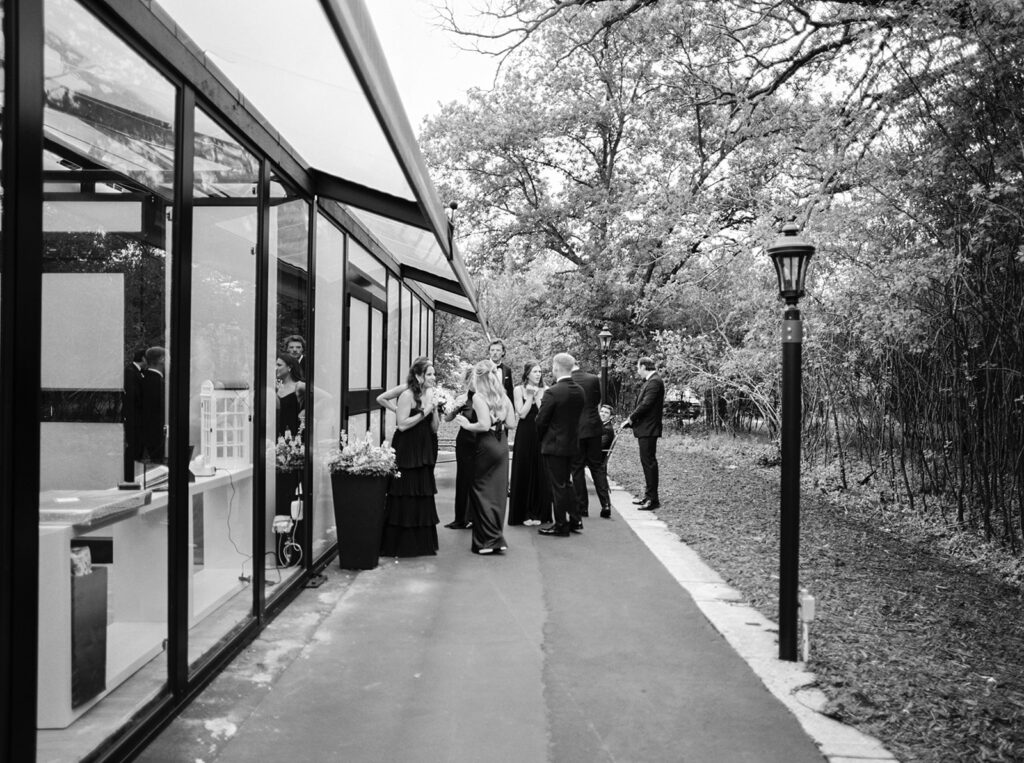 A black and white photo shows bridesmaids in chic black gown getting ready for a wedding at a chaska mn wedding venue