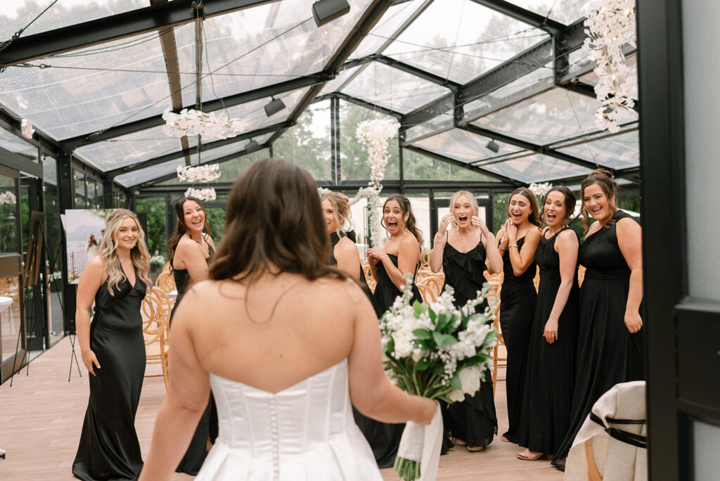 A first look between a bride & her bridesmaids is photographed at Woodland Glasshaus, a Bavarian Downs wedding venue 
