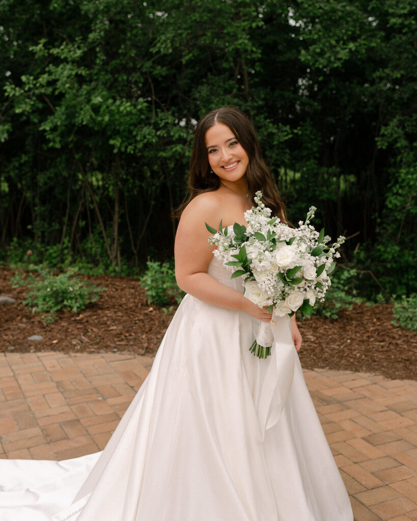 A bride in a strapless wedding gown holds an elegant white bouquet at her Bavaria Downs wedding at Woodland Glasshaus