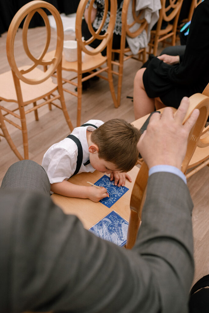 A child does scratch art after his ring bearer responsibilities at a bavaria downs chaska wedding