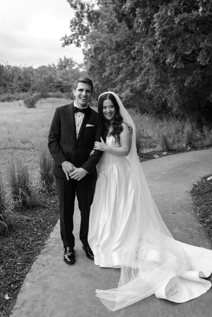 A black and white image shows newlyweds smiling and leaning into each other in a bridal portrait taken at their Bavaria Downs wedding