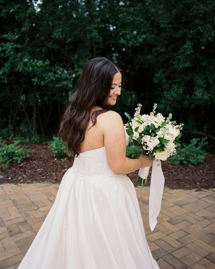 A bridal portrait taken by wedding photographers in minnesota depicts a bride in a strapless white gown holding an elegant bouquet of white roses