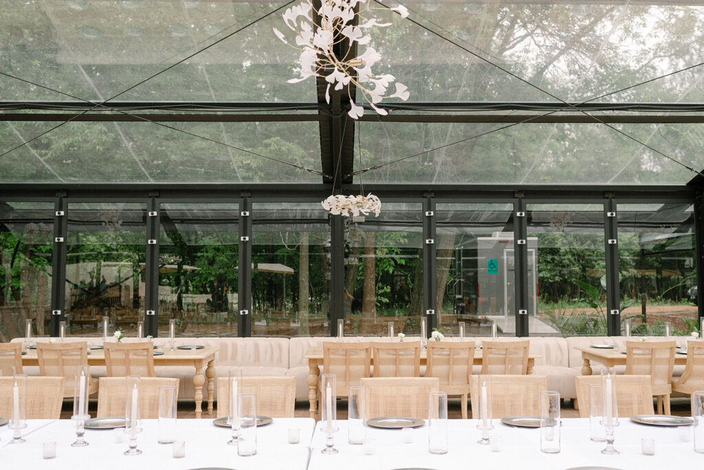 The dining atrium at Woodland Glasshaus, a Bavarian Downs wedding venue, is decorated with tapered candles and hurricane vases 
