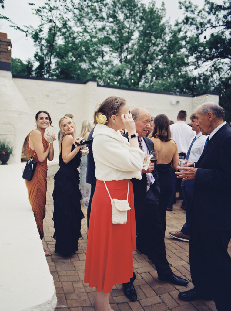 Wedding guests at one of the outdoor wedding venues in minnesota enjoy cocktail hour on the patio at Woodland Glasshaus