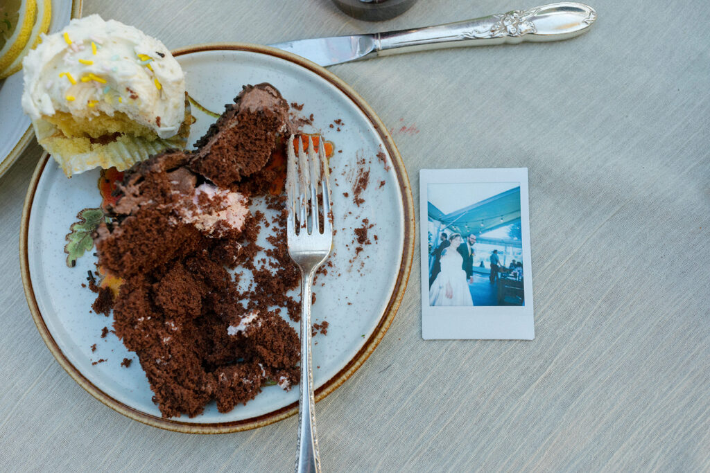 A polaroid is photographed next to a plate of chocolate cake at a columbia gorge wedding reception 
