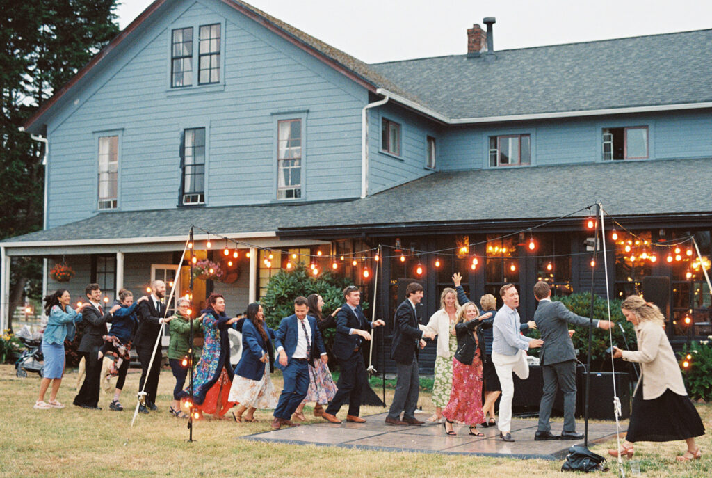 Wedding guests dance under bistro lights at a Tokeland Hotel wedding in Tokeland Washington 