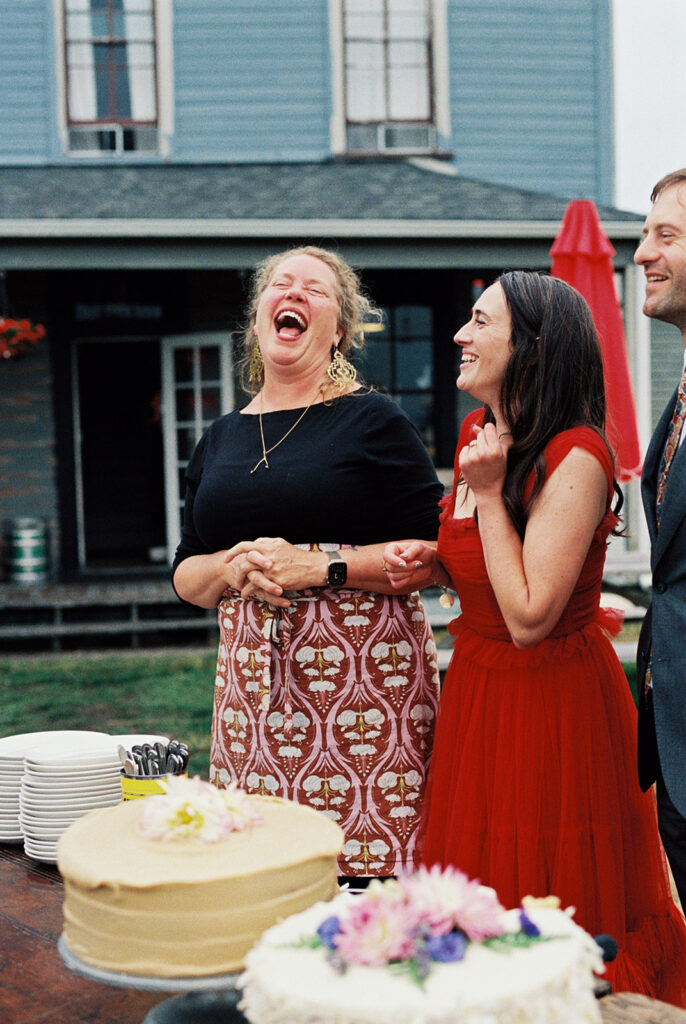 A chef at The Tokeland Hotel and Restaurant laughs next to a bride in a red dress at their wedding reception held at the WA hotel