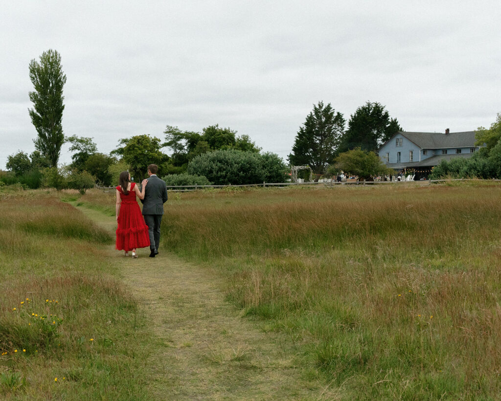 A bride and groom walk down a grass path in their wedding attire at before their wedding at the Tokeland Hotel Tokeland WA