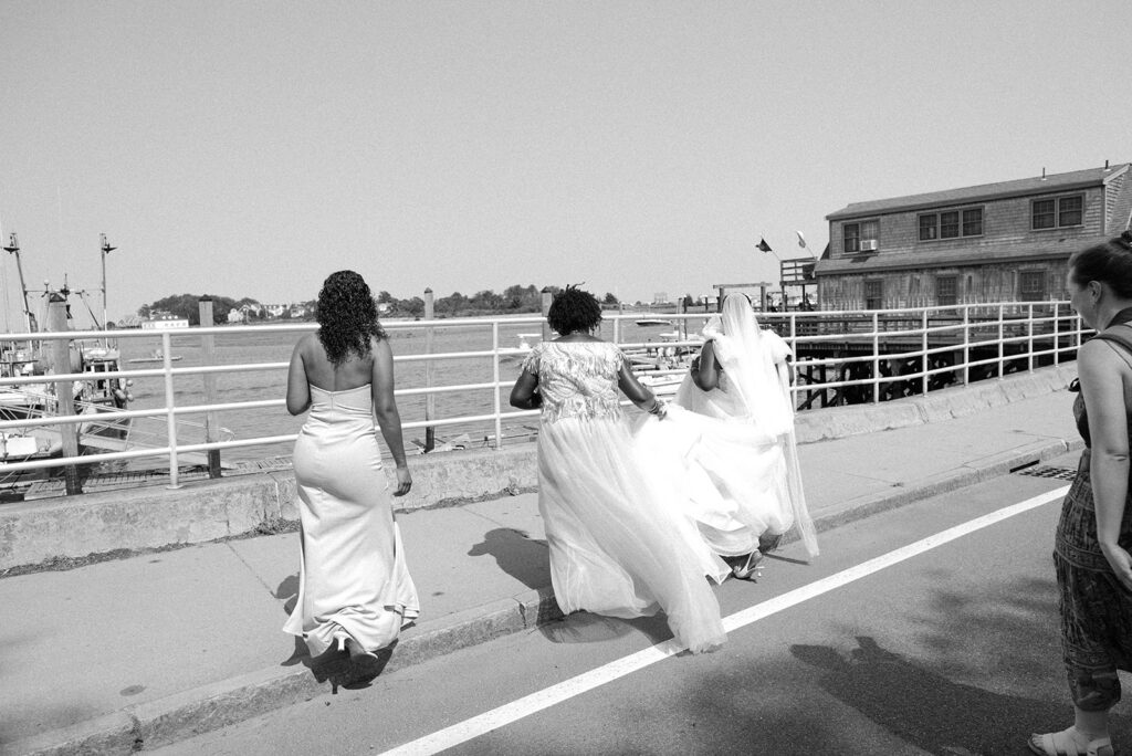 A bride walks with her bridal party next to the harbor at Barker House 