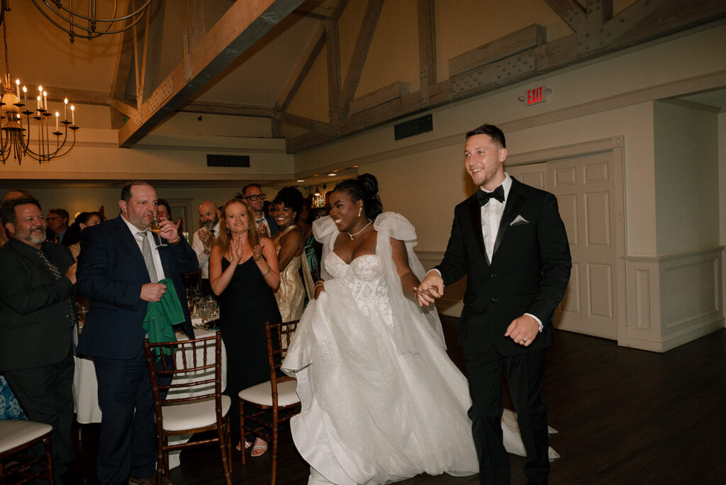 Newlyweds enter their wedding reception with smiles at Barker House by Wedgewood Weddings in Scituate MA