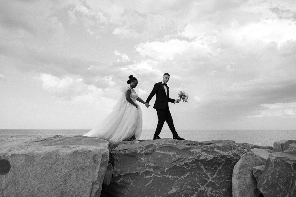Newlyweds walk hand in hand along the shore following their nuptials at Barker House, one of the most sought-after waterfront wedding venues ma