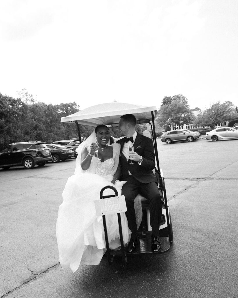 Newlyweds are transported via golf cart to their wedding reception in this black and white image taken at Barker House by Wedgewood Weddings 