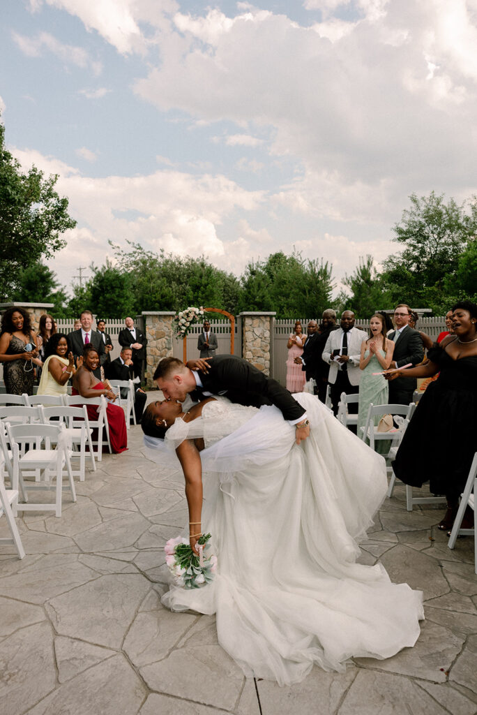 A groom dips his bride for a kiss at the end of the aisle following their barker tavern wedding