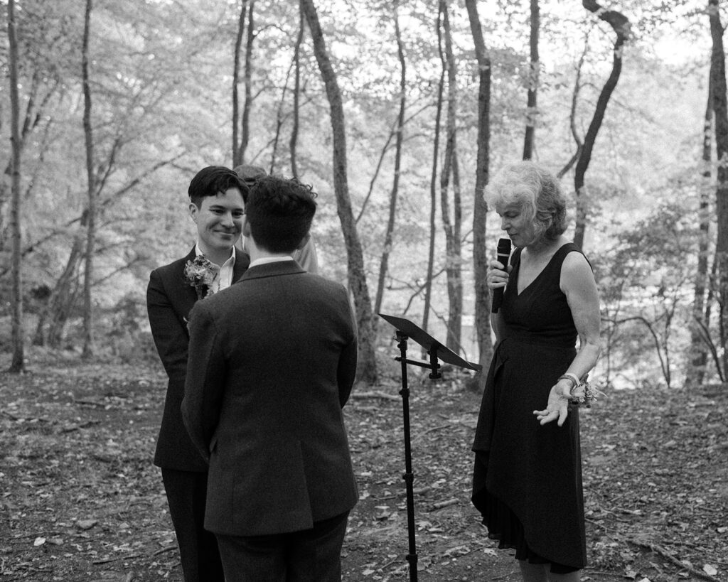 A black and white image depicts an initmate lgbtq+ ny wedding ceremony in the forest