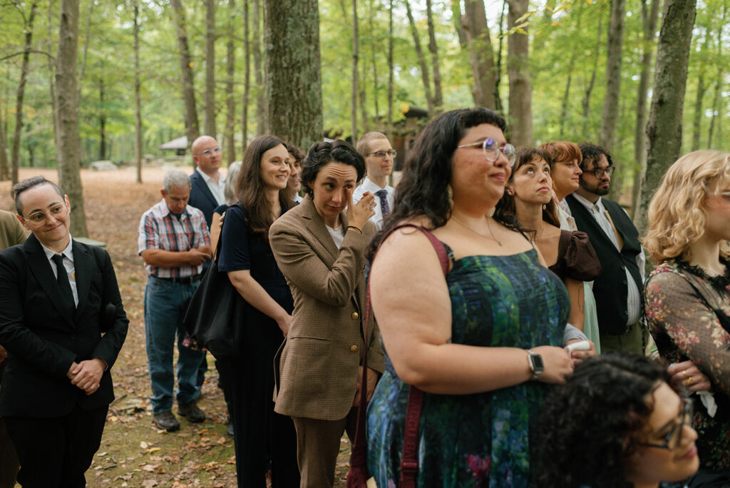 Emotional wedding guests smile as they watch a forest ceremony at mountain lakes park westchester