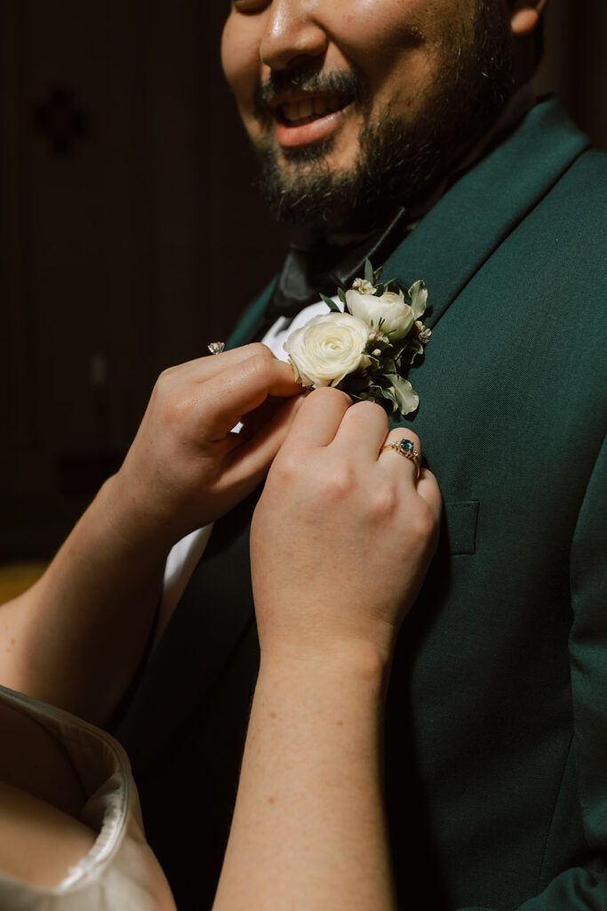 A white rose boutonniere is pinned upon a groom at a Seattle Washington wedding 